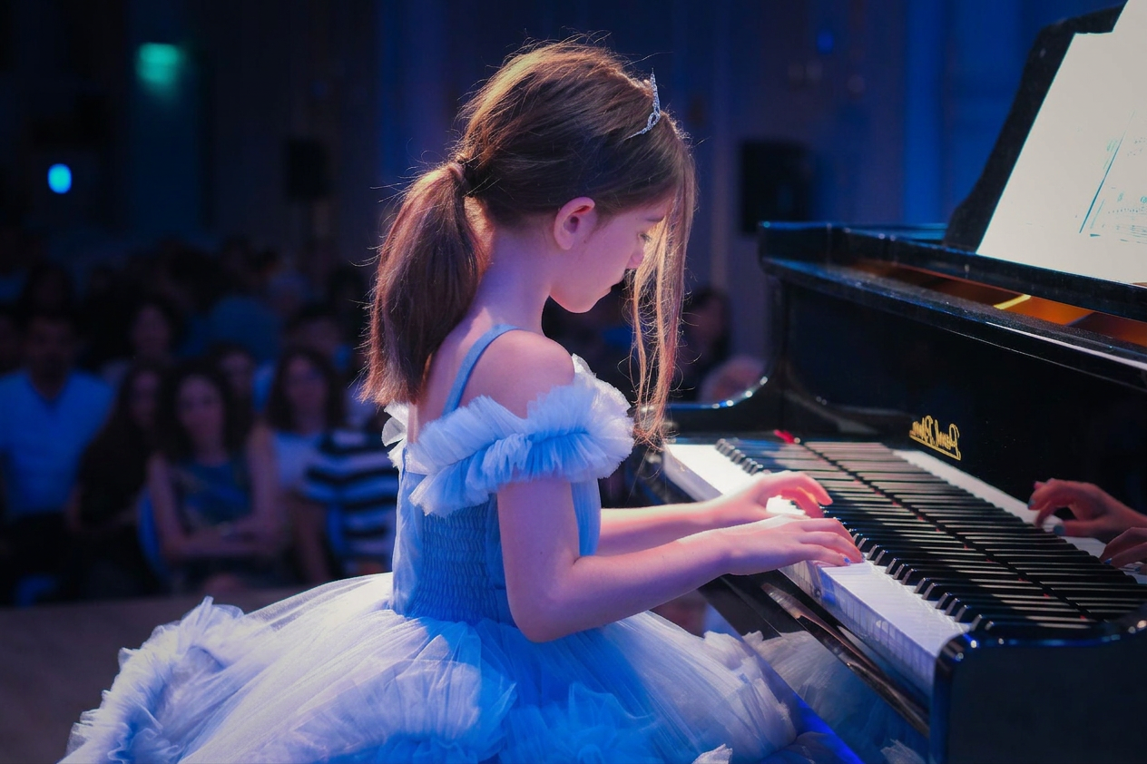young girl performing piano recital in blue dress